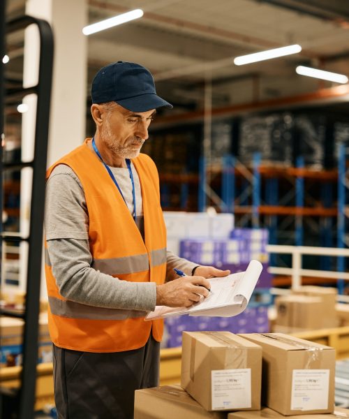 mature-worker-goes-through-checklist-while-preparing-packages-for-further-distribution-in-warehouse-