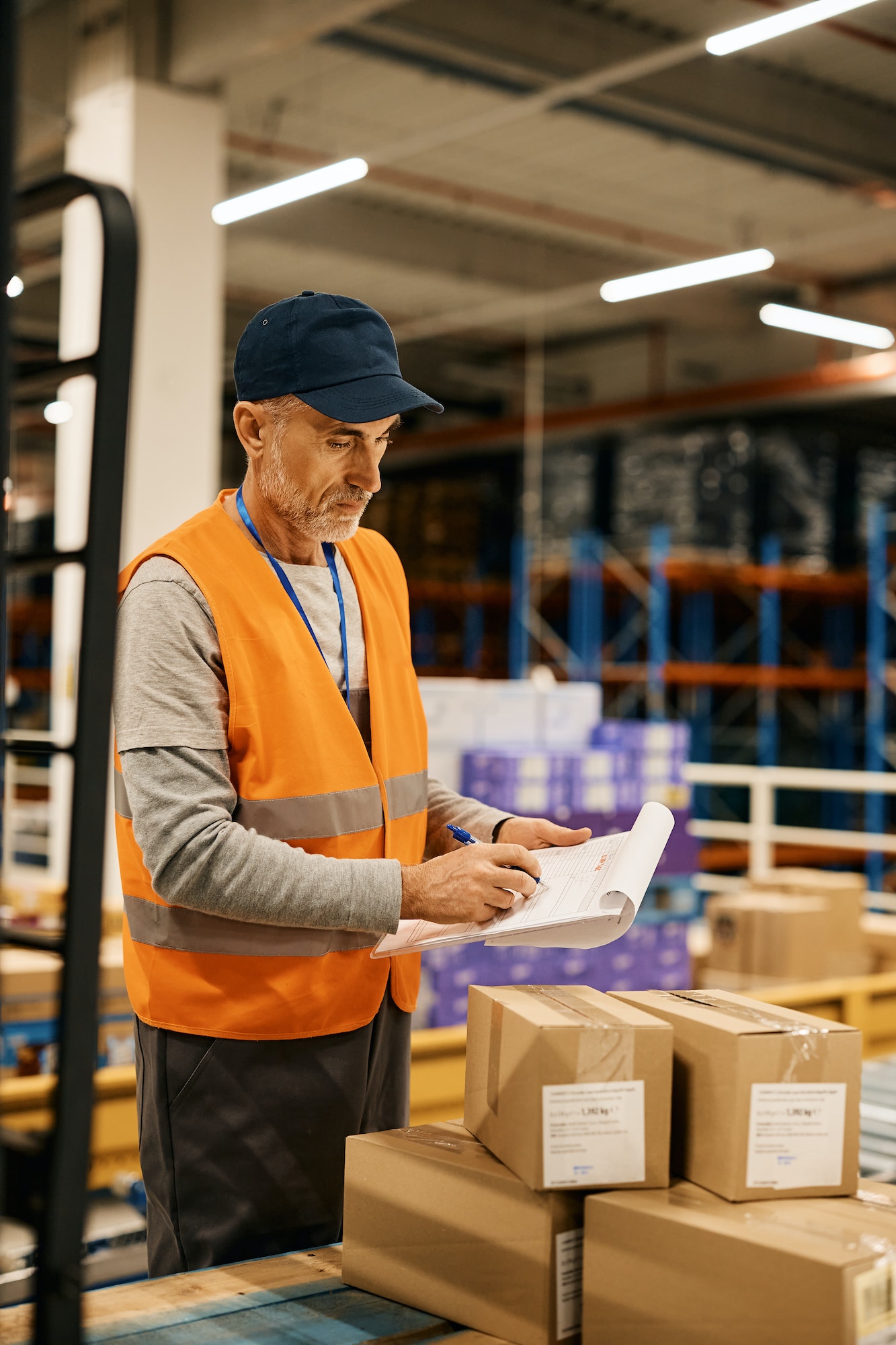mature-worker-goes-through-checklist-while-preparing-packages-for-further-distribution-in-warehouse-
